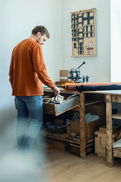 Samec koželužna pracující se strojem ruční tiskárny řezací vzor na materiál kožené dílny — Stock fotografie