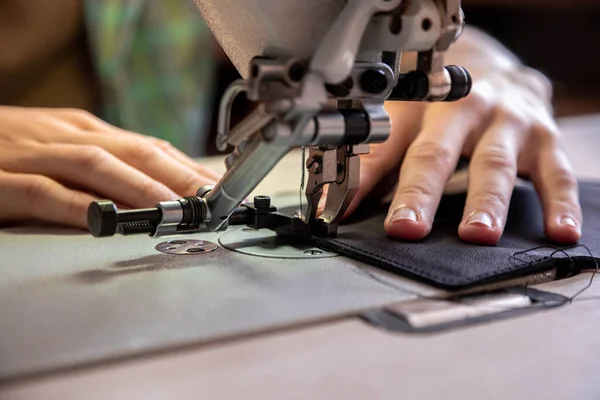 Close up craftsman hands sew stuff blank for wallet use sewing machine. Working at leather workshop — Stock Photo, Image