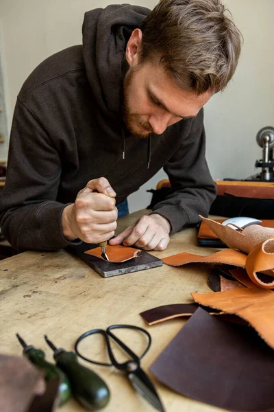 Craftsman machines edge of natural stuff workpiece use professional curly knife. Leather workshop — Stock Photo, Image