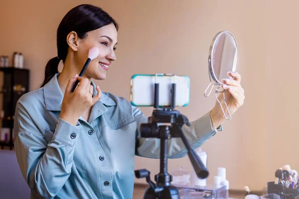 Feminino visagista beleza blogueiro aplicando maquiagem uso escova e espelho tiro vídeo uso smartphone — Fotografia de Stock