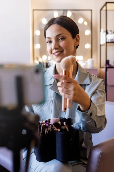 化粧品を適用するためのブラシを選択してvlogコンサルティングを記録する幸せな女性の美しさブロガー — ストック写真