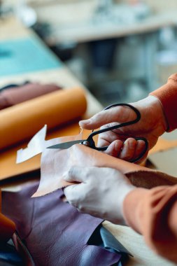 Zanaatkar doğal malzemeyi kesiyor. Makas kullanıyor. Deri atölyesinde çalışma süreci