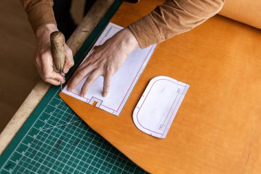 Erkek bronzlaştırıcı deri atölyesinde çalışırken kesim şeması yapıyor. El yapımı oluşturma
