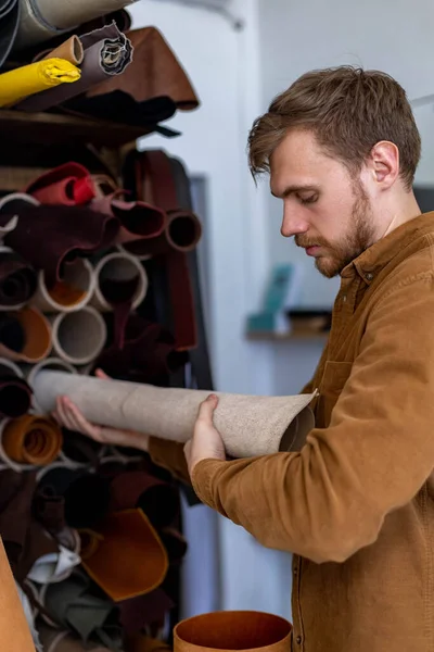 Closeup artesão masculino tendo pacote de material para trabalhar na oficina de couro. Fabricação de couros — Fotografia de Stock