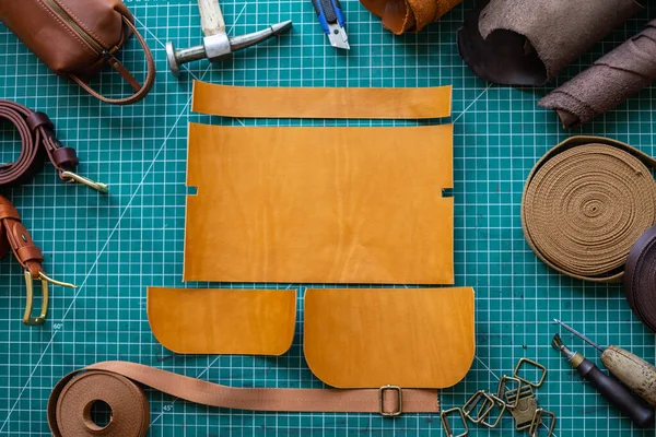 Process cutting scheme of bag with equipment and materials. Male tanner working at leather workshop