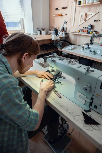 Fechar as mãos artesão costurar coisas em branco para a carteira usar máquina de costura. Trabalhando na oficina de couro — Fotografia de Stock