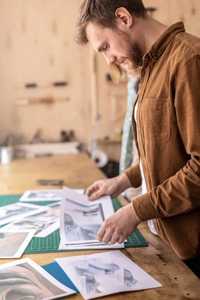 Muž profesionální koželužna vypadající obrázky papírové fotografie práce příklady ručně vyrobených kožených řemesel — Stock fotografie