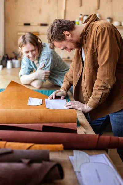 Řemeslník rozbaluje balík věcí z přírodního materiálu, který pracuje v kožené dílně. Kožené — Stock fotografie