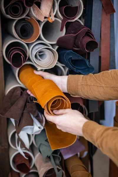 Closeup male craftsman taking material bundle for working at leather workshop. Making leathercraft — Stok fotoğraf