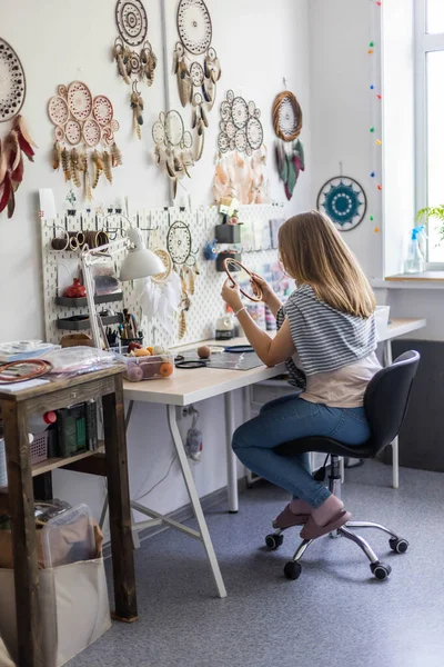 Maestro femenino creando Dreamcatcher trabajando en el taller con plumas y materiales —  Fotos de Stock