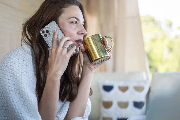 Happy beautiful woman talking smartphone holding tea mug relaxing at summer outdoor terrace — Fotografia de Stock