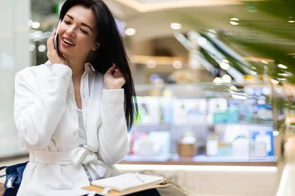 Mujer alegre de negocios hablando teléfono inteligente sonriendo tener emoción positiva en el centro comercial moderno —  Fotos de Stock