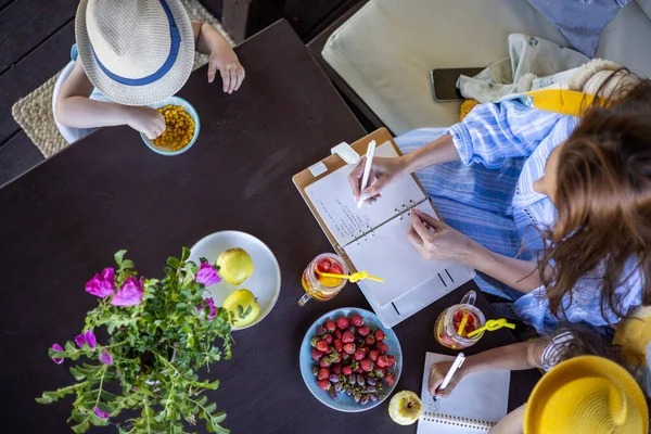 Top view business planificación femenina tomando notas relajándose con dos niños felices en la terraza de verano — Foto de Stock