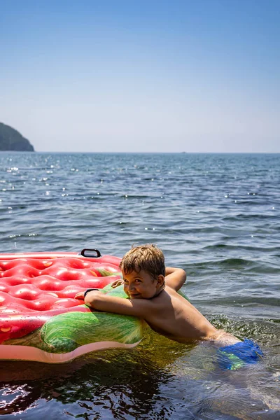 Saf deniz suyuyla çevrili şişme kauçuk çilek cankurtaran şamandırasında yüzen komik çocuk. — Stok fotoğraf