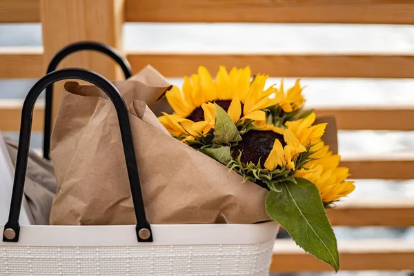 Stylish female white handbag things notepad, cozy scarf and seasonal blossom yellow sunflowers