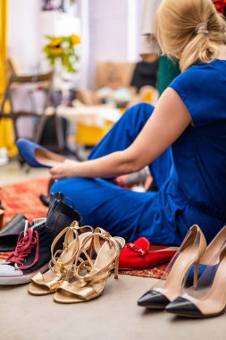 Moda stüdyosunda ayakkabı deneyen mutlu sarışın kadın ya da alışveriş sırasında alışveriş yapan butik.