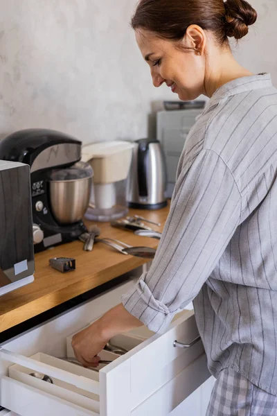 modern housewife tidying up kitchen cupboard during general cleaning or tidying up