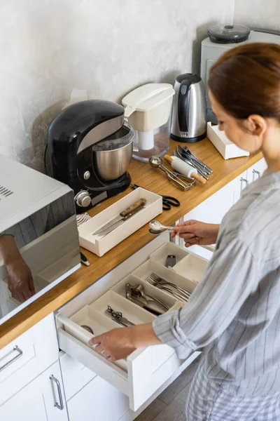 Ama de casa moderna ordenar armario de la cocina durante la limpieza general o ordenar —  Fotos de Stock