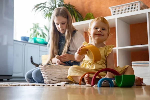 Baby girl in dress stacking rainbow arch block construction building ecological wooden toy tower — Stock Photo, Image