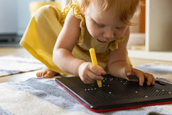 Nettes Baby Mädchen kindische Tablette magnetische Zeichnung mit Kugeln Erstellung von Pixelgrafiken auf Kunststofftafel — Stockfoto