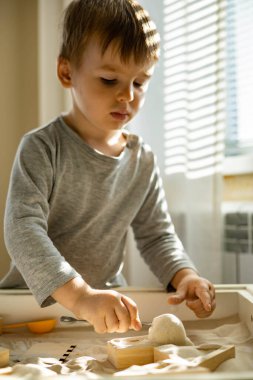 Kendi kendini geliştiren sevimli çocuk evde kinetik kum havuzu kullanıyor Maria Montessori metodu kullanıyor