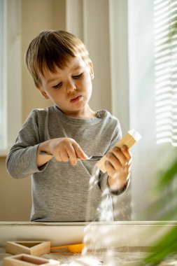 Kendi kendini geliştiren sevimli çocuk evde kinetik kum havuzu kullanıyor Maria Montessori metodu kullanıyor