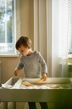 Kendi kendini geliştiren sevimli çocuk evde kinetik kum havuzu kullanıyor Maria Montessori metodu kullanıyor
