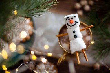 Kremayla süslenmiş bir kardan adam. Kakaolu altın kupa ve Noel süsü. Kar taneleri şeklinde zencefilli ekmek..
