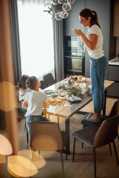 엄마는 토픽 뷰를 딸 과 아들 이 설탕으로 진저브레드를 장식하는 사진을 찍는다. 멋진 가정 식사와 주방. — 스톡 사진