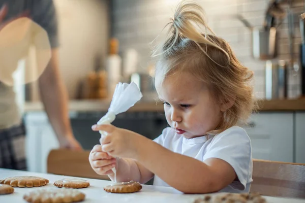 Piccola ragazza carina decora pan di zenzero con glassa di zucchero. Preparazione per il concetto di Natale. — Foto Stock