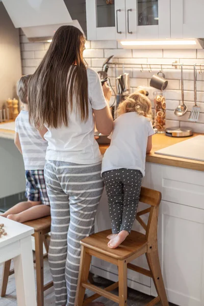 Mama i córka przygotowują lukier do piernika w domowej kuchni. Bij mikserem. Dziewczyna pomaga kobiecie.. — Zdjęcie stockowe