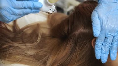 Profesyonel kozmetolojistin kafatası derisine kapalı alanda modern trikoloji uygulaması..