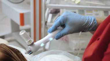 Kozmetik uzmanı, tıbbi güzellik kliniğinde kafa derisi yüzen kadınlarda yenilikçi trikoloji cihazıyla saç terapisi uyguluyor..