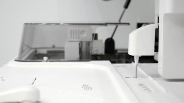 Modern tıbbi laboratuvar ortamında biyokimyasal analiz sırasında otomatik laboratuvar analizcisi kesin hareketler ve örnek testleri gerçekleştirir..