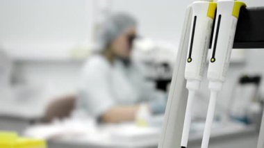 Bulanık laboratuvar teknisyeniyle laboratuvar mikroskobunda kapalı mekanda çalışan mikro-pipetlere yakın çekim..