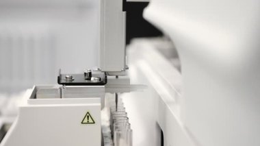 Modern tıbbi laboratuvar ortamında biyokimyasal analiz sırasında otomatik laboratuvar analizcisi kesin hareketler ve örnek testleri gerçekleştirir..