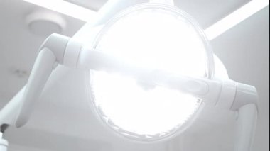 Modern bir diş kliniğinde dişçi lambası, kapalı alanda parlak tıbbi aydınlatma ekipmanları açılıyor..