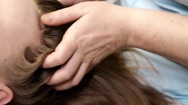 Estetik kliniğindeki kafa masajı terapisini kapat. Güzellik uzmanı, rahatlamak ve güzellik salonundaki dolaşımı iyileştirmek için saç ve kafa derisine nazikçe masaj yapar..