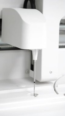 Bir örnek porta inen otomatik analiz pipetinin dikey makro görüntüsü, temiz bir klinik ortamda kesin tanı otomasyonunu ve modern laboratuvar ekipmanlarını gösteriyor.