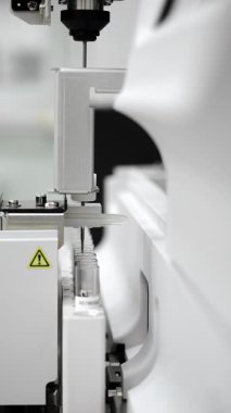 Modern klinik laboratuvar ortamında örnek tüpleri işlemeye hazırlanan otomatik laboratuvar analiz iğnesinin dikey olarak kapatılması hassas tanı ekipmanlarını gösterir..