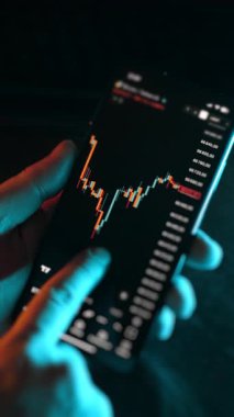 Uygulama ekranında soyut şamdan şeması olan akıllı telefonu kapat. Düşük ışık altında finans piyasası dengesizliği, yatırım riski ve dijital ticaret kavramı.