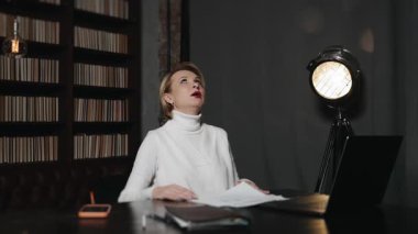 Stresli iş kadını ofis işi sırasında evrakları atıyor ve yüzünü örtüyor. Modern ofiste aşırı çalışma, hüsran, tükenme ve duygusal baskı..