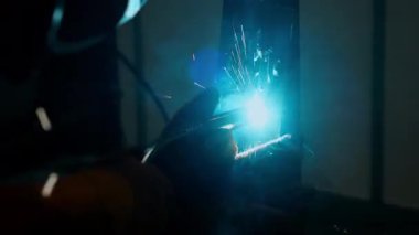 Fabrika atölyesindeki metal üretim sürecinde çelik yapı üzerinde parlak kıvılcımlar saçan sanayi işçisi.