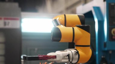 Otomatik üretim fabrikasında çalışan endüstriyel robotik kol. Endüstriyel otomasyon ve akıllı fabrika üretimi için kullanılan modern robot teknolojisi.