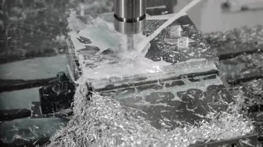 Modern imalat fabrikasındaki hassas endüstriyel mekanik işlemler sırasında CNC değirmen makinesinin metal kısmını soğutucu sıvıyla kesmesi.