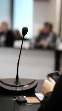 İş konferansı sırasında ya da kurumsal sunum sırasında arka planda bulanık seyircilerle konuşmadan önce toplantı odasındaki masada mikrofon konferansı.