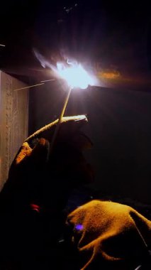 Endüstri işçisi metal borularda kaynak yaparak endüstriyel atölyede parlak kıvılcımlar üretiyor..