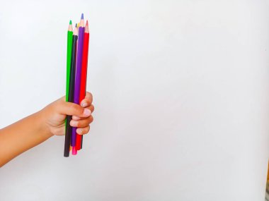 Asyalı çocuk elinde renkli kalemlerle temiz beyaz bir arkaplanda fotokopi alanı var. Yaratıcılık, eğitim, okul malzemeleri, sanat faaliyetleri, çocukluk eğitimi ve hayal gücü kavramı.