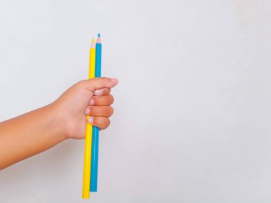 Asyalı çocuk elinde renkli kalemlerle temiz beyaz bir arkaplanda fotokopi alanı var. Yaratıcılık, eğitim, okul malzemeleri, sanat faaliyetleri, çocukluk eğitimi ve hayal gücü kavramı.