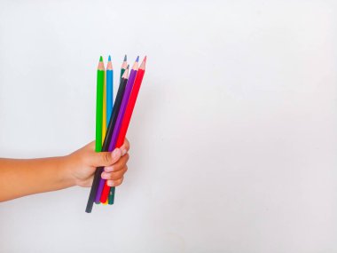 Asyalı çocuk elinde renkli kalemlerle temiz beyaz bir arkaplanda fotokopi alanı var. Yaratıcılık, eğitim, okul malzemeleri, sanat faaliyetleri, çocukluk eğitimi ve hayal gücü kavramı.